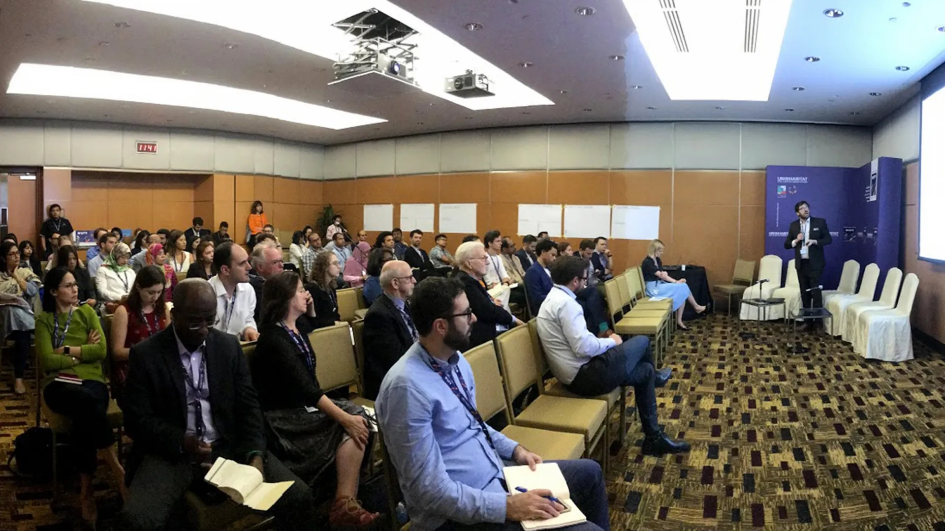 Audience from the ninth session of the World Urban Forum facing towards a presentation by 100RC Director Samuel Carter.